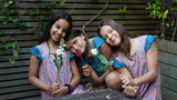 3 girls smiling wearing dresses and holding roses