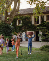 Boy walks happily whilst holding a plush giraffe toy, wearing soft long pyjamas in orange dinosaur.