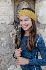 Brunette girl in a blue leopard long-sleeve pyjama top holds up three sprigs of lavender and smiles.