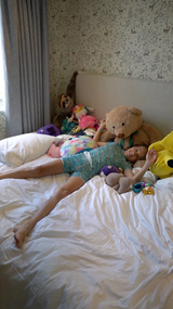 Boy lies snuggly on his bed wearing the short pyjamas in aqua blue colour with the fruit splash design