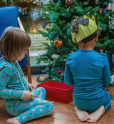 2 children wearing pyjamas in front of a christmas tree