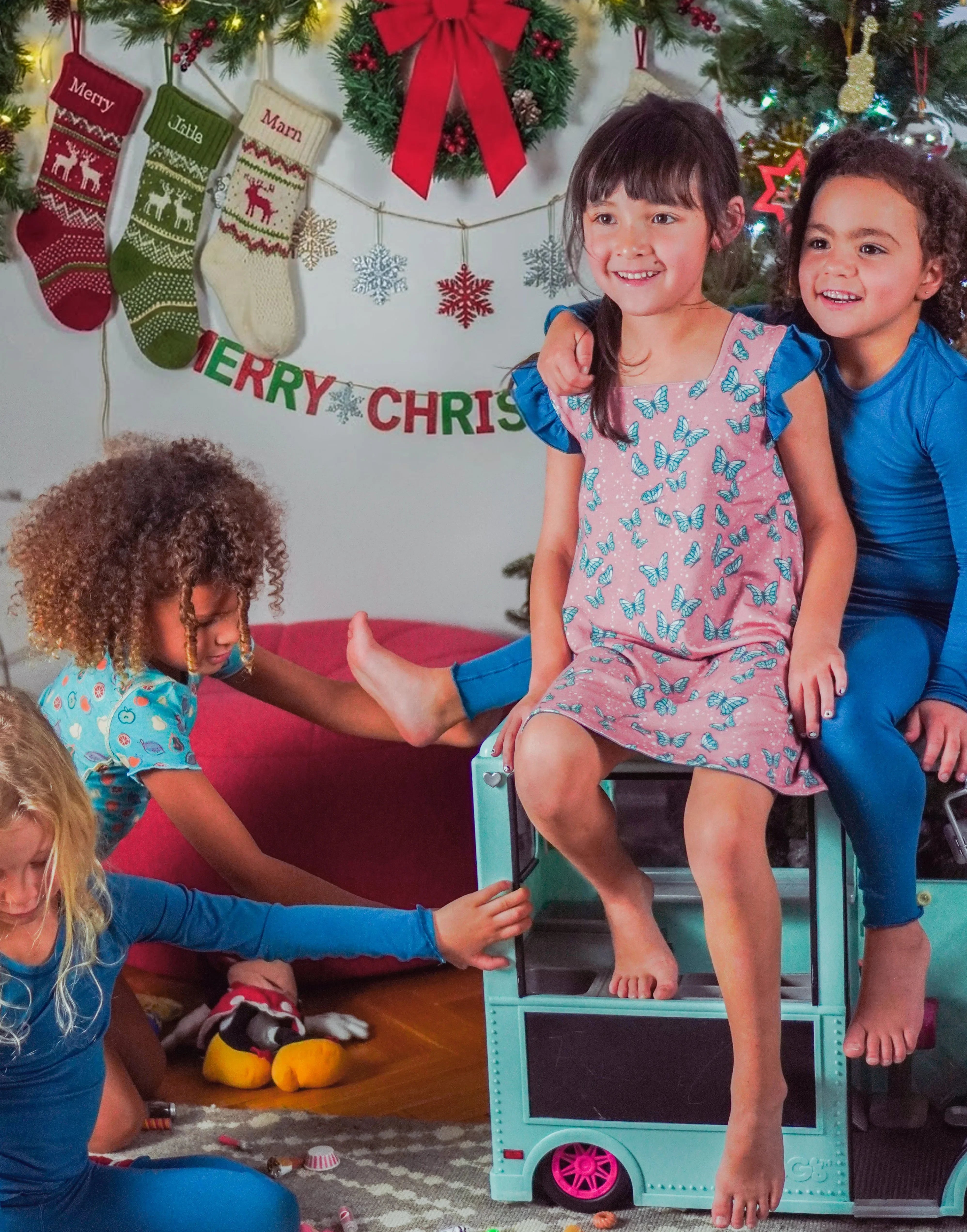 Girl in pink Bouncing Butterfly reversible dress with a friend in matching pyjamas riding a toy van
