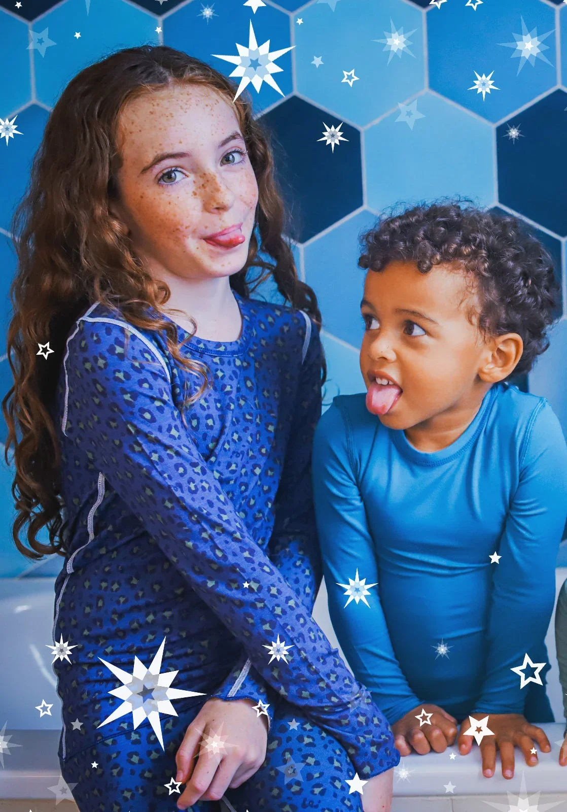 a girl wearing a leopard print pyjamas looking cheeky and a boy wearing a blue pyjama looking at her