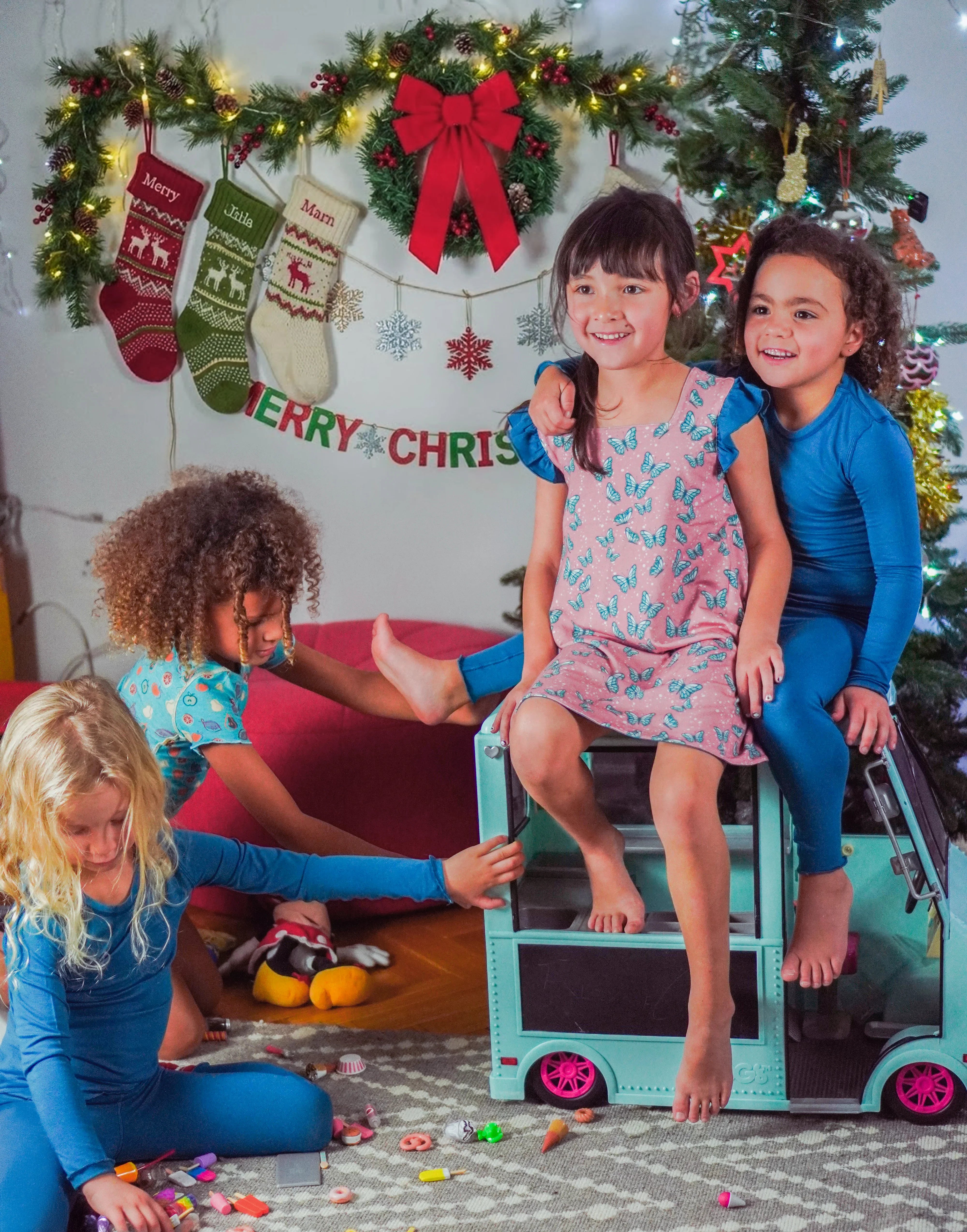 Children playing together with toy van in a festive room decorated for Christmas.