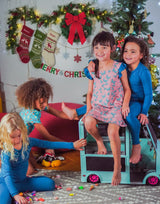 Children playing together with toy van in a festive room decorated for Christmas.