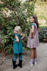 Two girls playing outdoors in teal and pink Bouncing Butterfly reversible dresses, TENCEL sensory-friendly kidswear